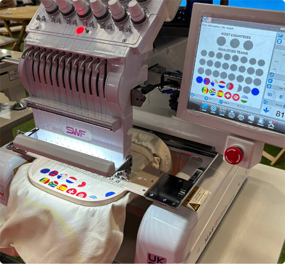 SWF embroidery machine stitching a World Cup-inspired design onto a white tote bag